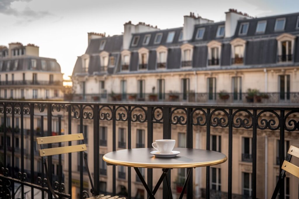Kaffeetasse auf einer Terrasse mit Blick auf Gebäude im Zentrum von Paris, Frankreich.
