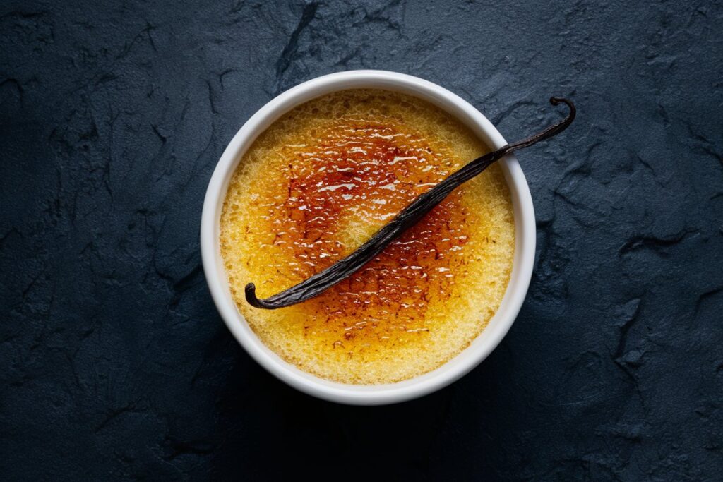 Köstliche Crème Brûlée mit Vanillegeschmack, goldbrauner karamellisierter Kruste, garniert mit einer frischen Vanilleschote.